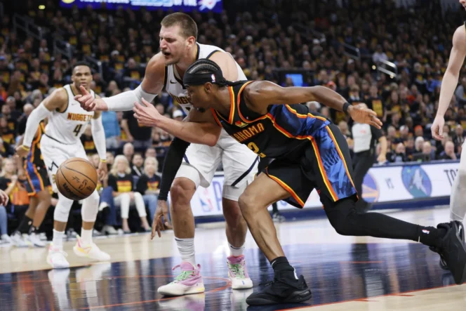 
					Pemain Oklahoma City Thunder, Shai Gilgeous-Alexander mencoba berebut bola liar dengan Nikola Jokic, pemain Denver Nuggets pada gim pertama Semifinal Wilayah Barat NBA 2025.