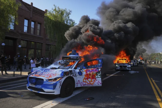 
					Beberapa taksi Waymo terbakar di dekat Metropolitan Detention Center, pusat kota Los Angeles, pada Minggu, 8 Juni 2025. (foto: AP/Eric Thayer)