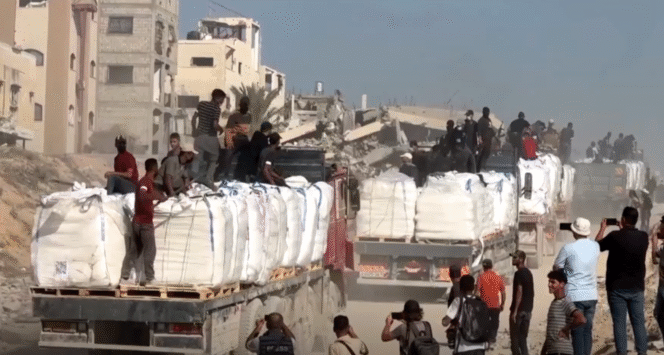 
					Tangkapan layar video truk-truk bantuan yang dinaiki puluhan orang bertopeng. (foto: REUTERS)