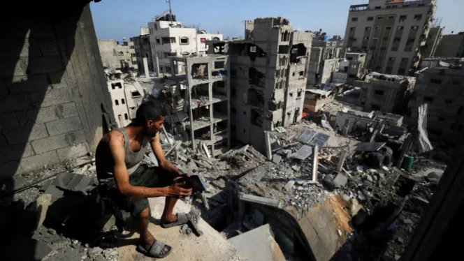 
					Seorang warga Palestina memandangi bangunan-bangunan yang hancur akibat serangan Israel di kamp pengungsi al-Shati, Gaza utara. (foto: REUTERS)