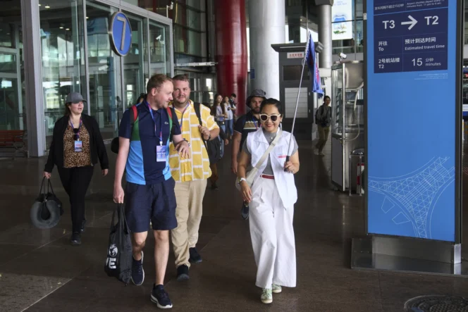 
					Pemandu wisata China sedang mengantarkan turis asing di Bandara Internasional Beijing. (foto: AP/Andy Wong)