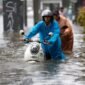 Warga berjalan menerobos banjir yang merendam jalan di Bangkok, Thailand.