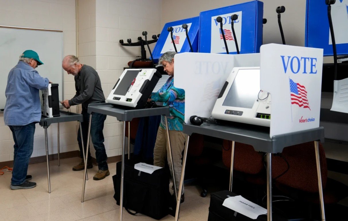Petugas pemilu menyiapkan mesin penanda surat suara di tempat pemungutan suara awal langsung di Asheville-Buncombe Technical Community College, 16 Oktober 2024, di Marshall, Carolina Utara. (AP Photo/Stephanie Scarbrough)