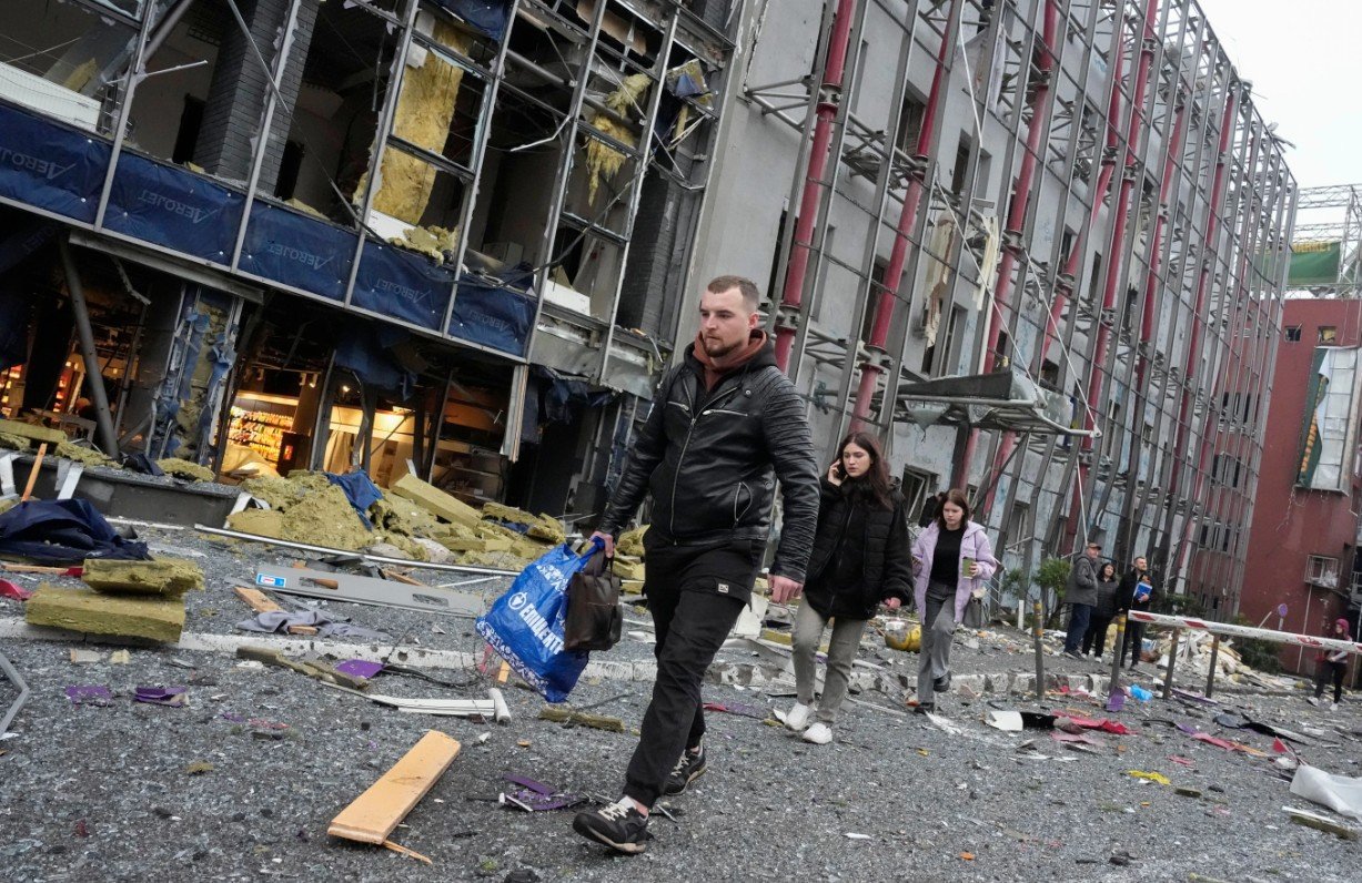 Warga membawa barang-barang mereka saat meninggalkan kantor usai serangan udara Rusia di Kyiv, Ukraina. Senin, 19 Oktober 2026. (AP Photo/Efrem Lukatsky)
